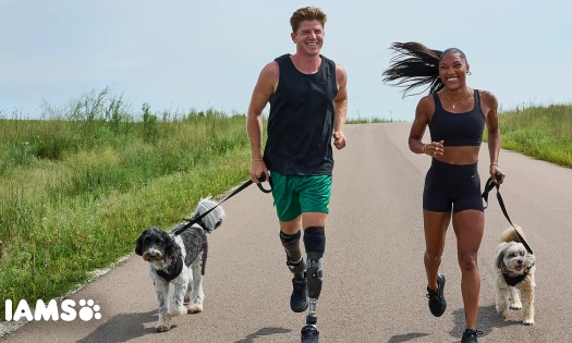 Two dog owners running with their pets