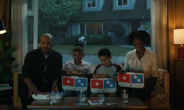 A family eating Domino's in their living room
