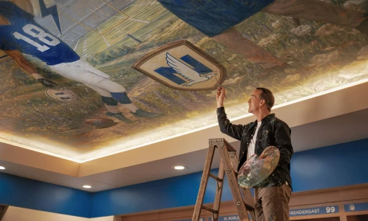 Peyton Manning painting a mural on the ceiling.
