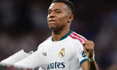 A pair of whiteout Mercurial Superfly 11 with Kylian Mbappé in his Real Madrid home jersey in the background.