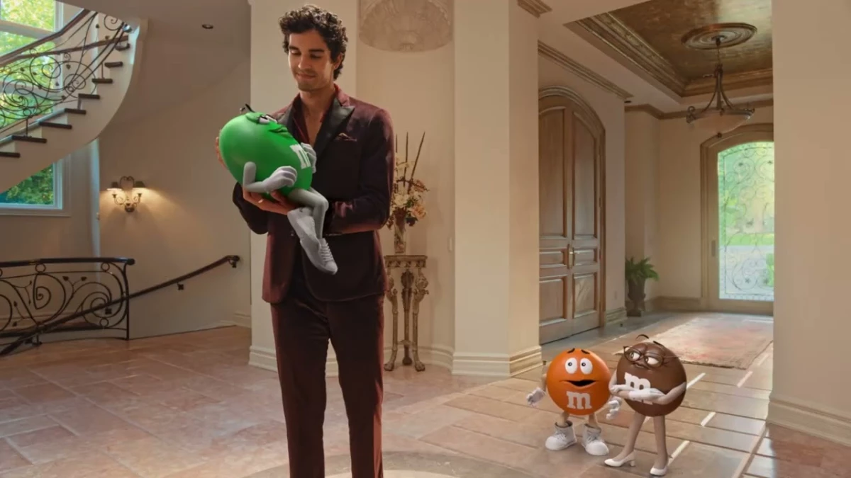 A man cradling an M&M's spokescandy while others look