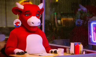 The (not) Laughing Cow sitting in a booth inside a diner