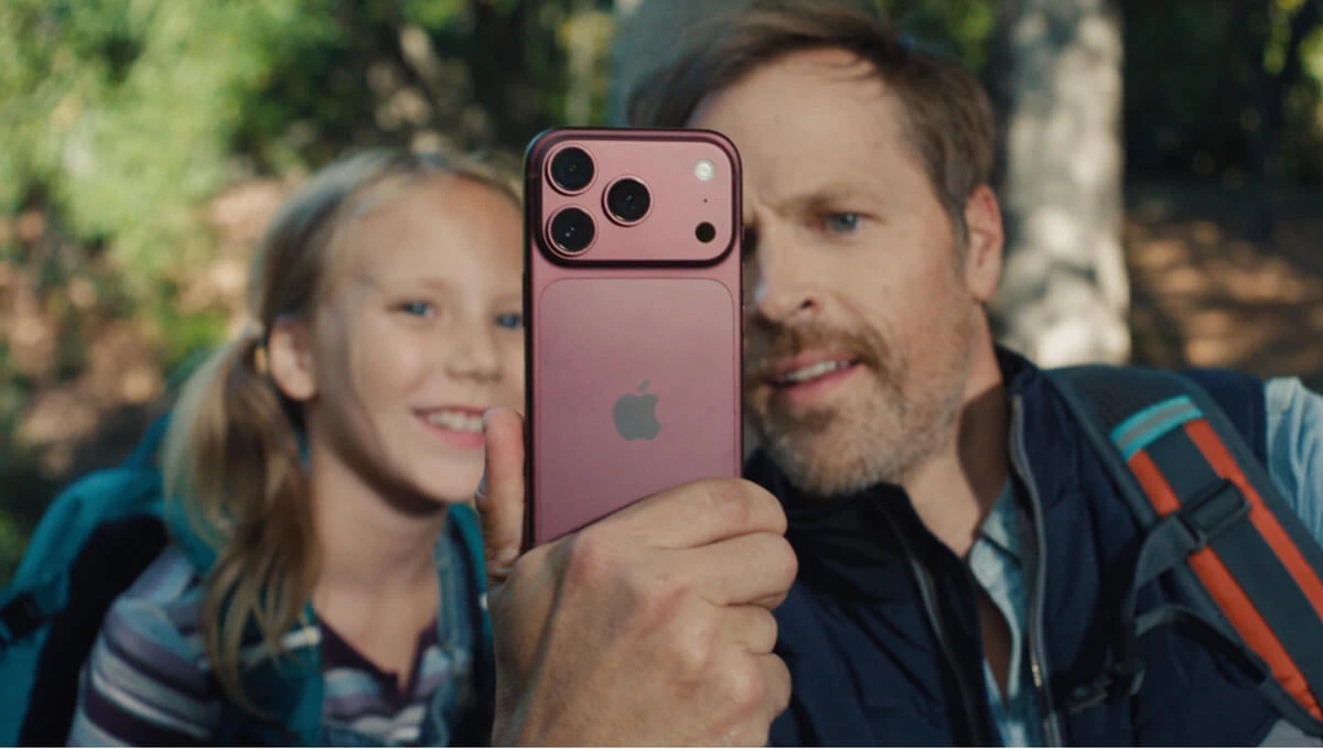 A man and his daughter looking into the screen of an iPhone 18