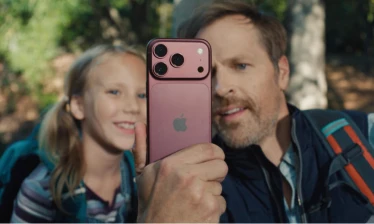 A man and his daughter looking into the screen of an iPhone 18