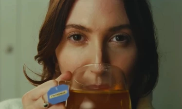 A woman sipping on her cup of Twinings tea