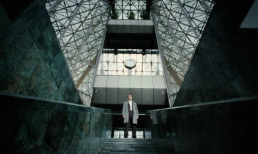 A cinematic shot of a man standing against intricate architecture