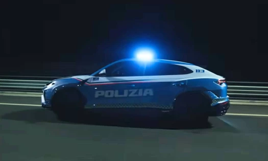 A cinematic shot of a Lamborghini Urus SE as a police car driving down a highway at night