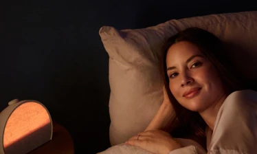 Olivia Munn lying beside her Hatch Sleep Clock