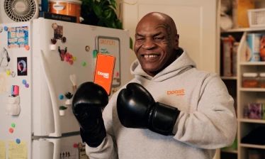 Mike Tyson holding up a phone with the Boost Mobile app opened