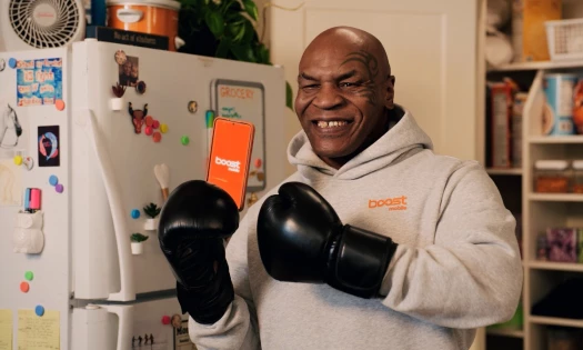 Mike Tyson holding up a phone with the Boost Mobile app opened