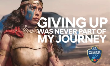 Young girl in a warrior outfit with the Hyundai Hope on Wheels painted handprint on her face.