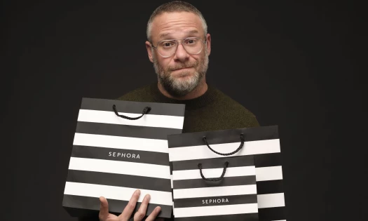 Seth Rogen holding three Sephora shopping bags.