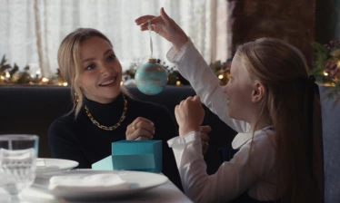 Amanda Seyfried putting Tiffany & Co jewelry on a young girl