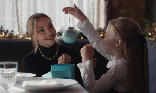 Amanda Seyfried putting Tiffany & Co jewelry on a young girl