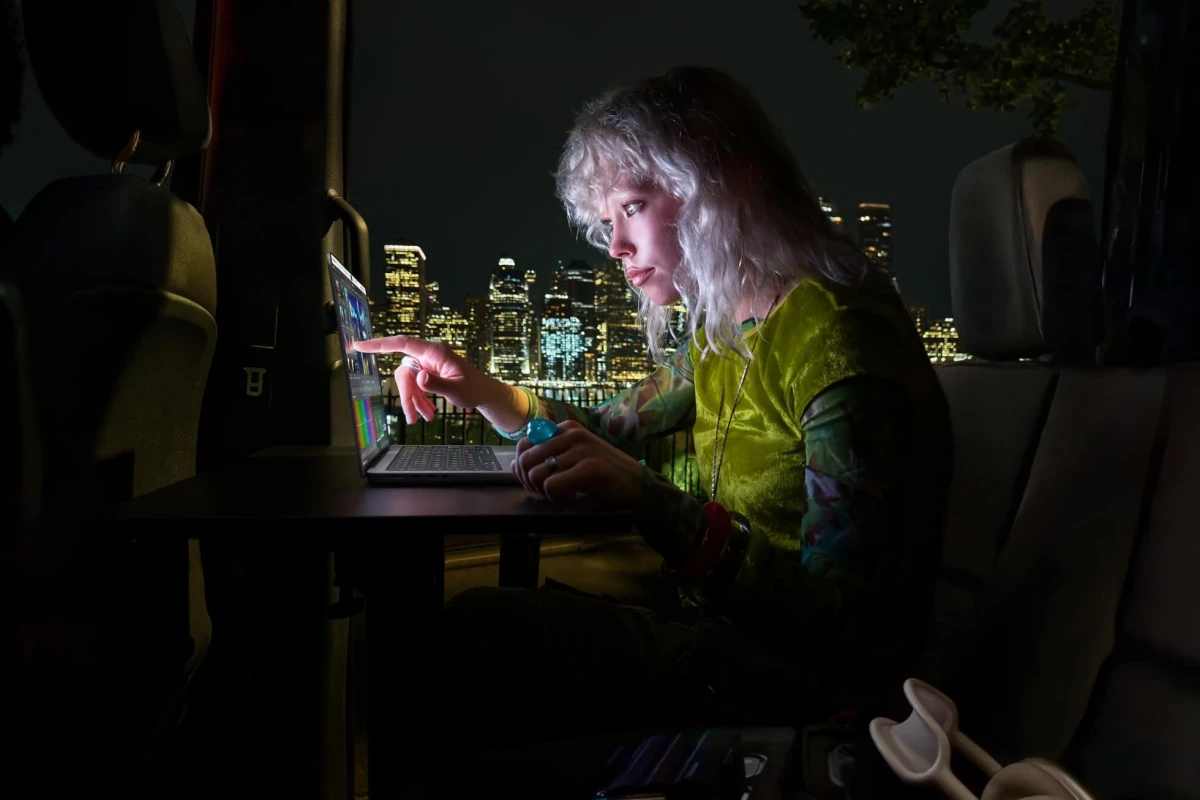 A woman works on the MacBook Pro in the dark using the touch control features