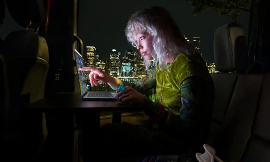 A woman works on the MacBook Pro in the dark using the touch control features