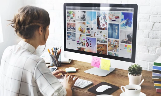 Best photo management software: Girl sitting on desk organizing photos on a Mac computer