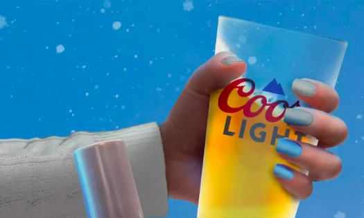 Close-up on woman's hand with blue nail polish holding beer glass with Coors Light logo