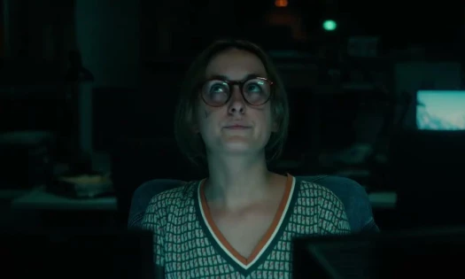 Screenshot of campaign video, woman with glasses shown working late in office