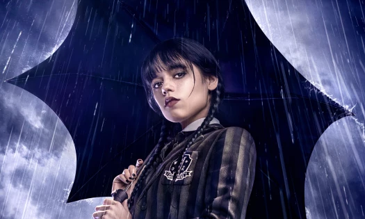 Jenny Ortega as Wednesday Addams in school uniform and holding a black umbrella as rain pours around her