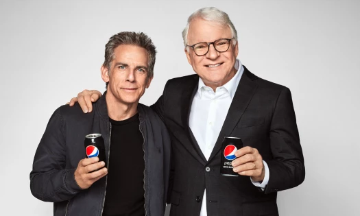 Ben Stiller and Steve Martin stand next to each other holding Pepsi cans