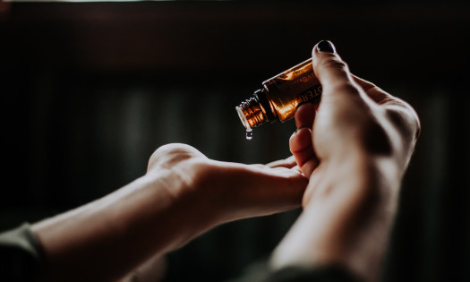 CBD oil being poured from glass bottle into palm