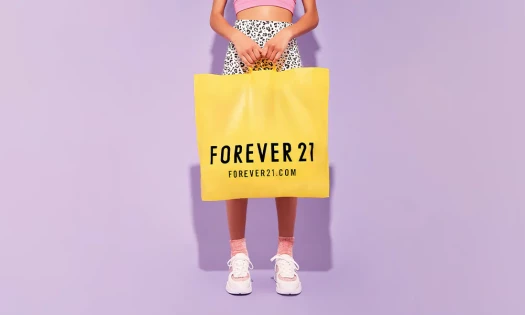 Young woman in colourful pink and animal print outfit holding yellow Forever 21 shopping bag