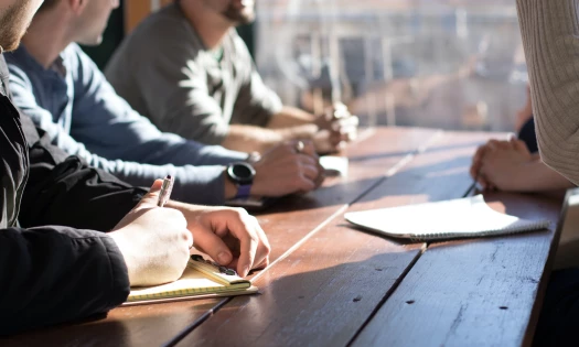 People sitting around a desk with notepads at work