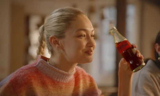 Gigi Hadid with a glass bottle of Coca-Cola in her hand