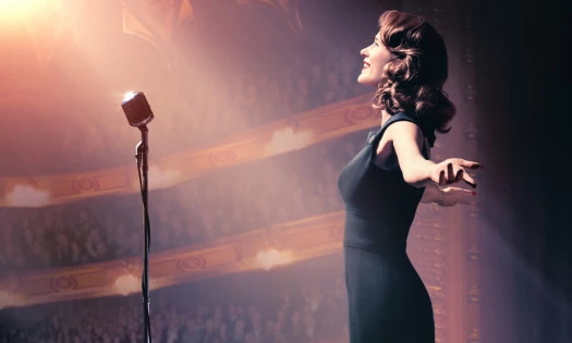 Midge Maisel facing a microphone on stage