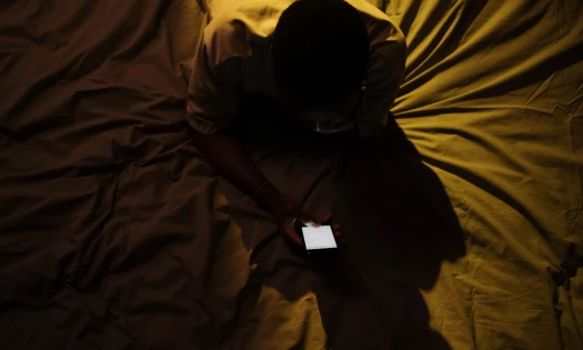 Man looking at his phone in the bed during night