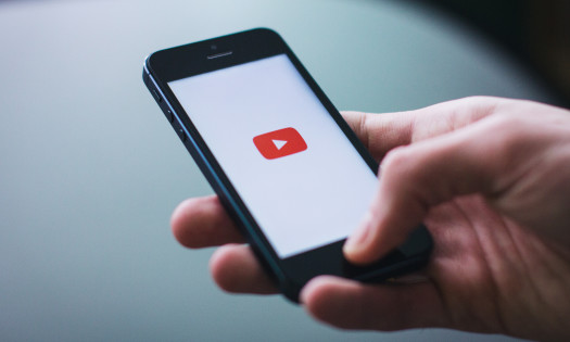 Hand holding smartphone with the YouTube application logo on the screen