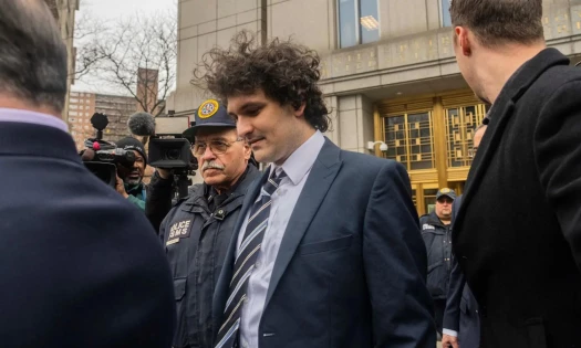 Photograph of Sam Bankman-Fried leaving the courthouse, surrounded by journalists and police officers
