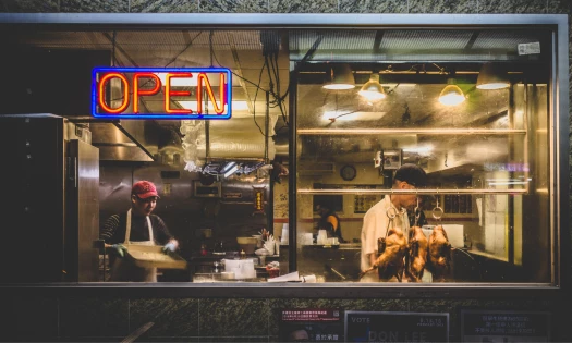 A view through a window, from the outside looking in, to two men working in a restaurant in Chinatown, New York City