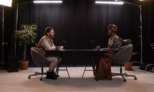 Image of two people in a studio, conducting a podcast