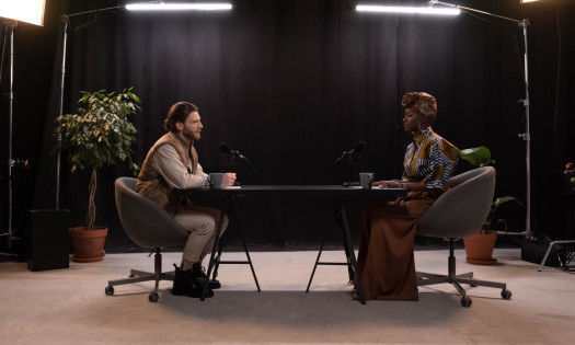 Image of two people in a studio, conducting a podcast