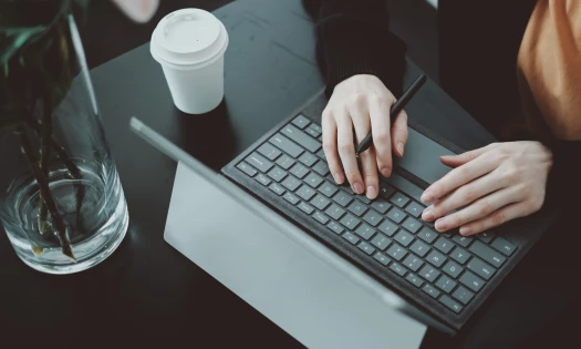 Close-up, aerial view of a person's hands working on a laptop