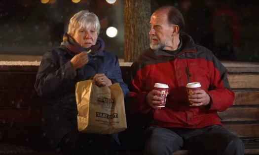 Still image captured from The Beefy Boys' Christmas 2023 ad of an old couple sitting on an outdoor bench at night