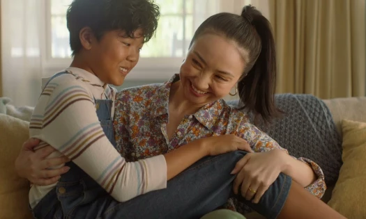 A grown boy sits on his mom's lap
