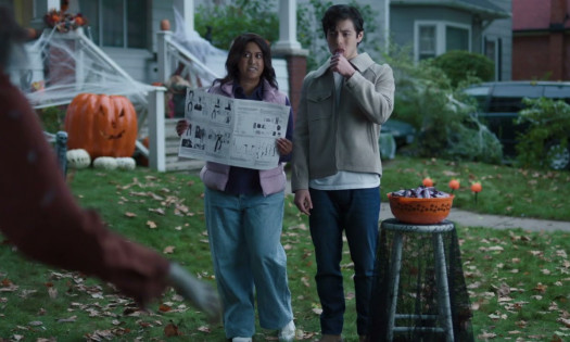 A woman and a man eating a Snickers glare at a zombie decoration