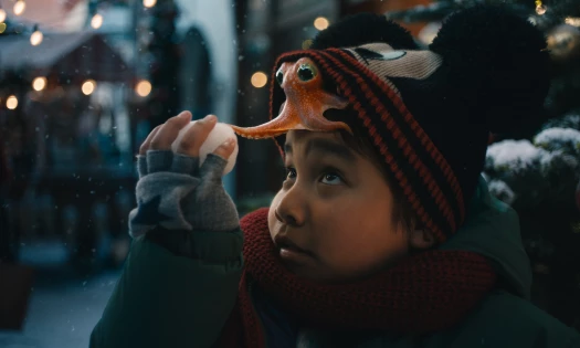An octopus on top of a boy's head touching a snow ball