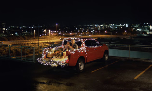 A father and daughter have Christmas dinner in a lit-up car at a hospital parking lot