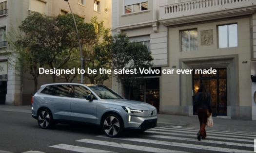 Volvo stopped at pedestrian crossing as woman crosses the street