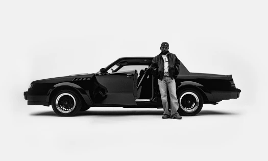 Photo of Kendrick Lamar standing in front of a car.