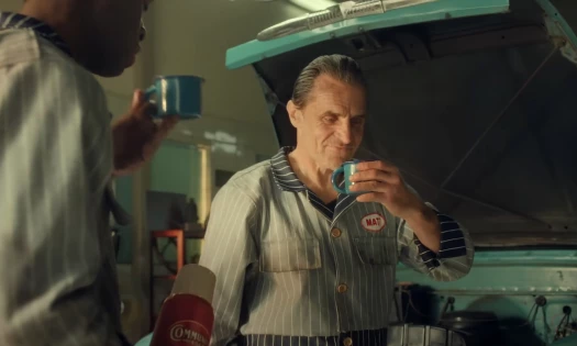 A mechanic drinks coffee with his colleague