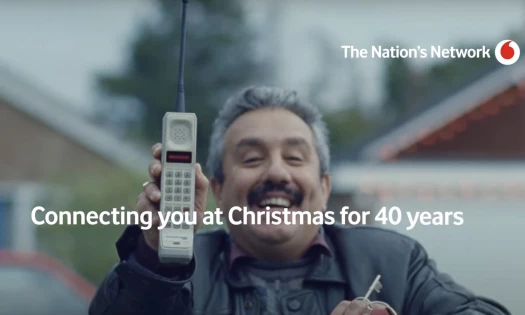 A man holding an ancient cell phone with the text: "Connecting you at Christmas for 40 years"