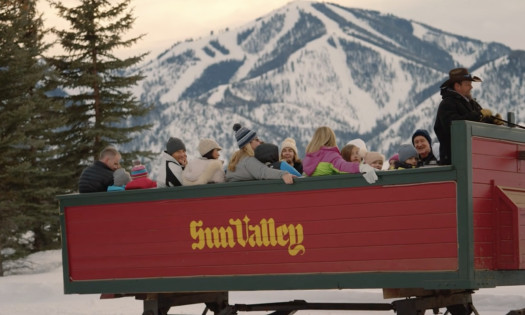 People riding a sleigh with Sun Valley imprinted on the side