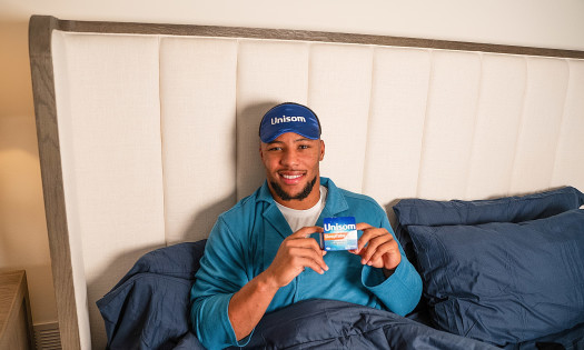 Saquon Barkley in bed holding a Unisom pack
