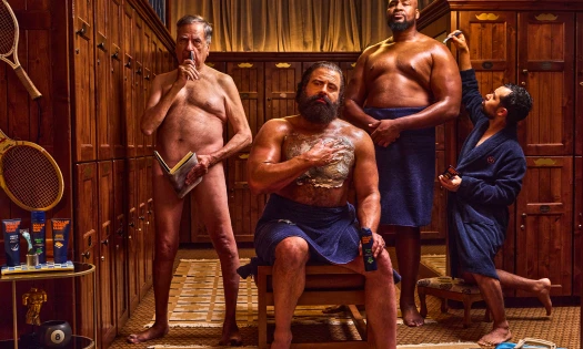 Four men in various states of undress are shaving different parts of their body