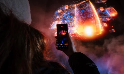 A woman taking a video of Samsung's colorful lantern hologram in the sky